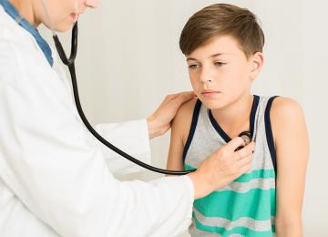 Influenza-Behandlung bei Kindern: Kind mit Grippe wird von einem Arzt untersucht.