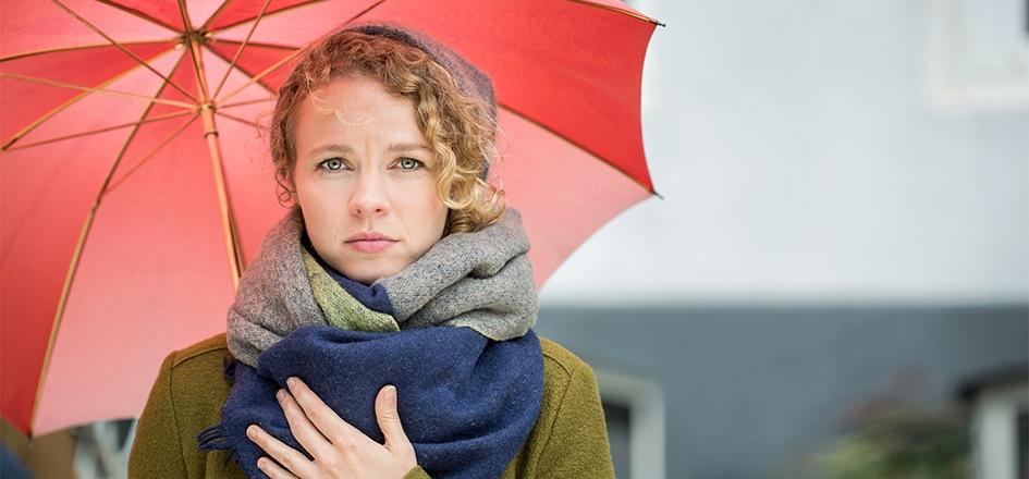 Erkältete Frau macht sich Gedanken über Erkältungsmythen.