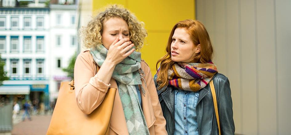 Erkältete Frau will ihre Freundin nicht mit einer Erkältung anstecken.  