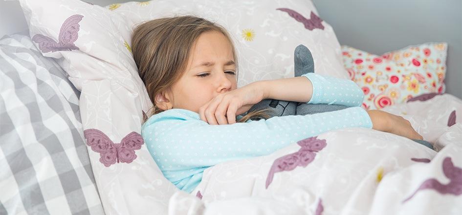 Bei Halsschmerzen liegt ein Kind erschöpft im Bett.